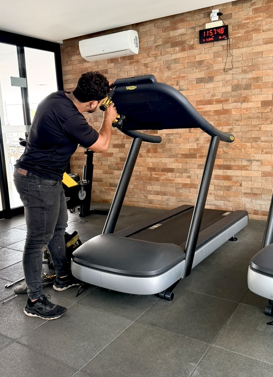 Técnico da Tec Fitness fazendo manutenção em uma esteira